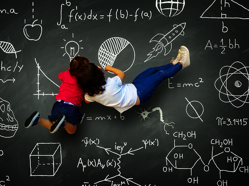 Two little writing girls on a blackboard with science subjects